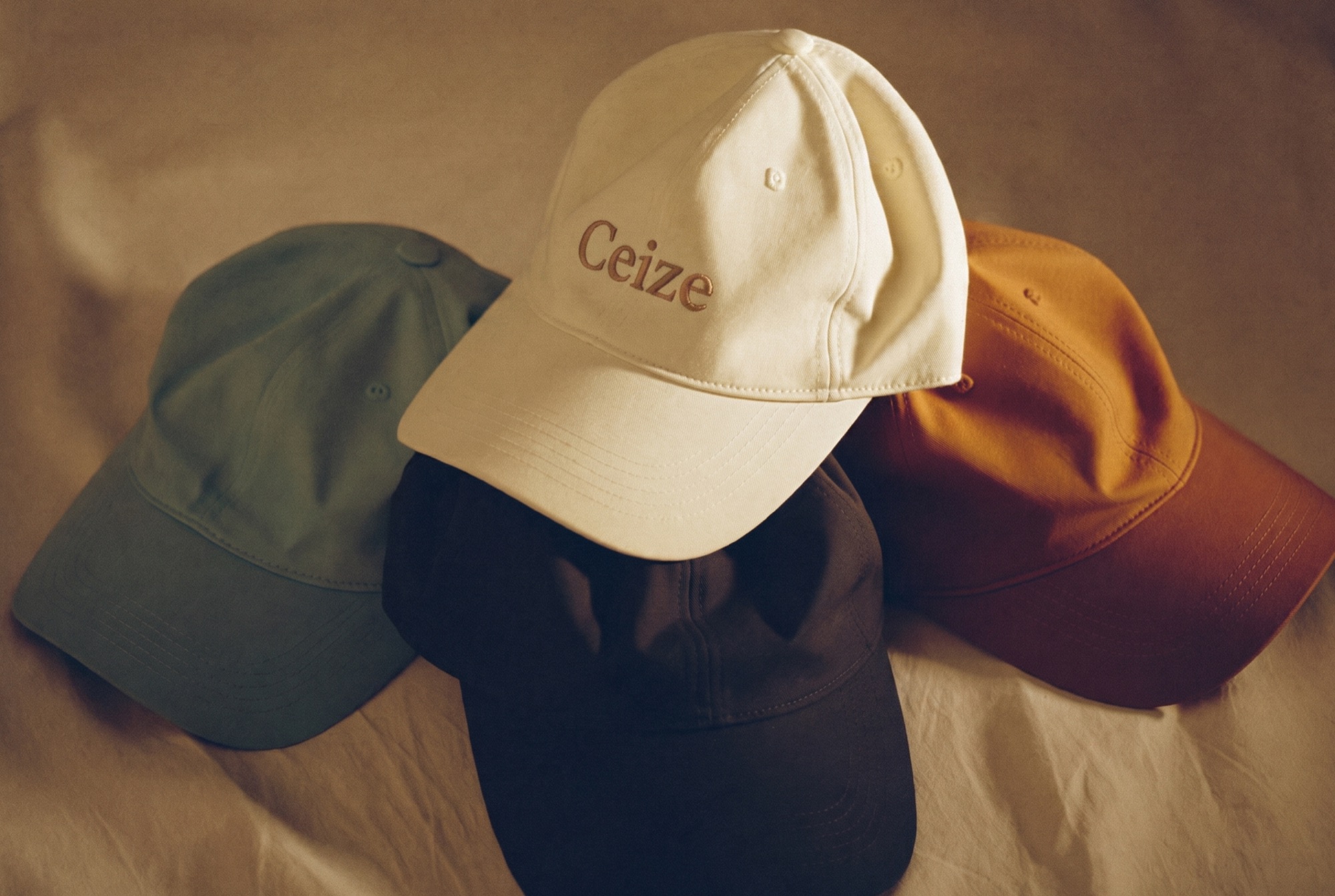 Still life of Ceize caps in cream, sage, navy and camel on linen